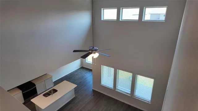 an empty room with wooden floor fan and windows