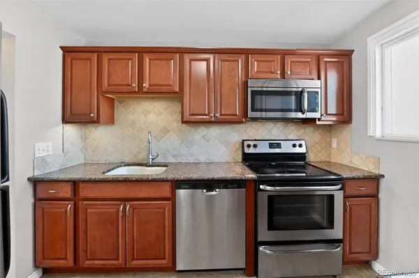 a kitchen with granite countertop wooden cabinets and a stove top oven
