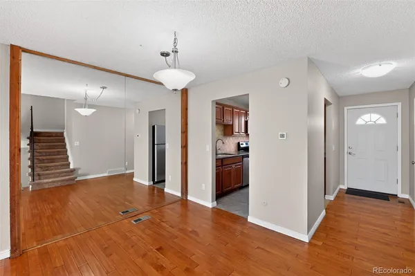 a view of a hallway with wooden floor and a kitchen