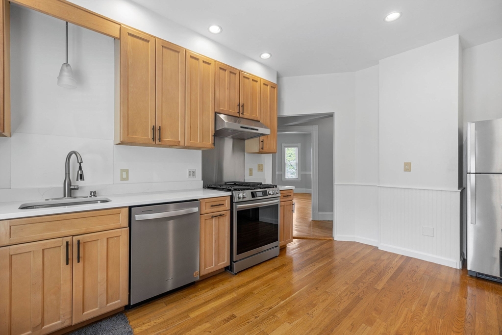 228 Langley Road Newton, MA 02459 - Photo 5 of 39 a kitchen with stainless steel appliances granite countertop a sink stove and refrigerator