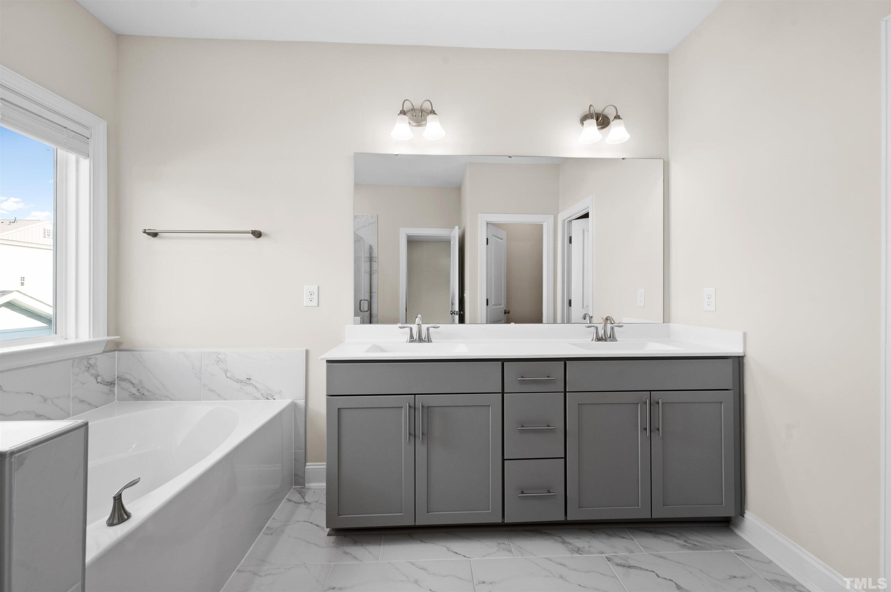 2917 Early Planting Avenue Apex, NC 27502 - Photo 27 of 41 a spacious bathroom with a bathtub sink and mirror