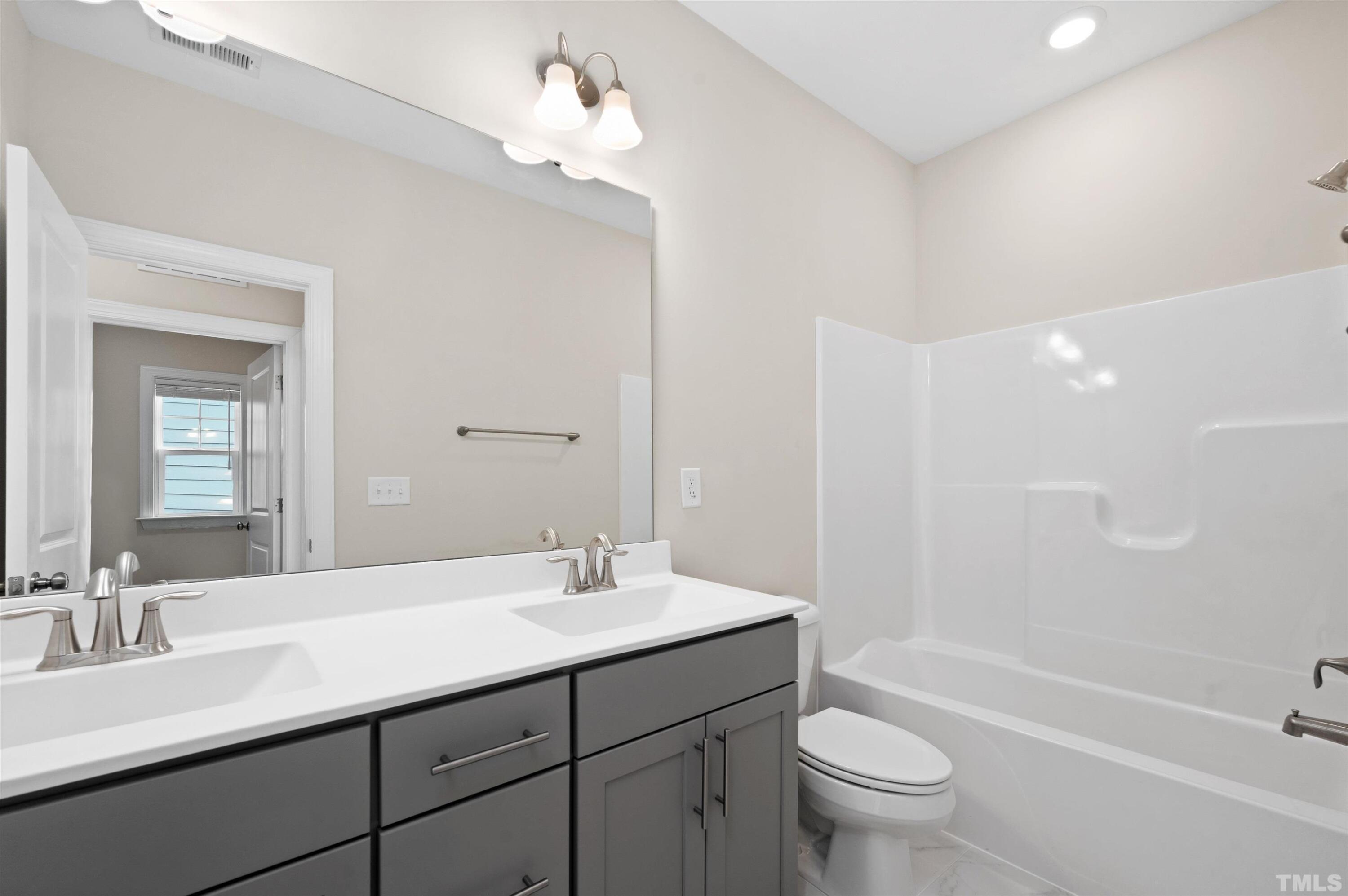 2917 Early Planting Avenue Apex, NC 27502 - Photo 31 of 41 a bathroom with a double vanity sink toilet mirror and bathtub