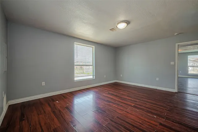 an empty room with wooden floor and windows
