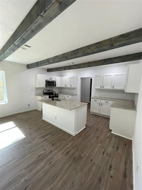 607 East Monterey Street Denison, TX 75021 - Photo 7 of 34 a large kitchen with stainless steel appliances a large counter top a wooden floors and a fireplace
