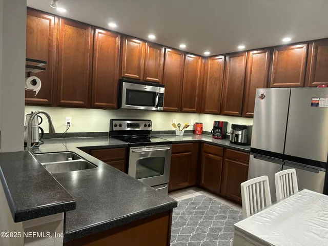 a kitchen with kitchen island granite countertop a sink stainless steel appliances and cabinets