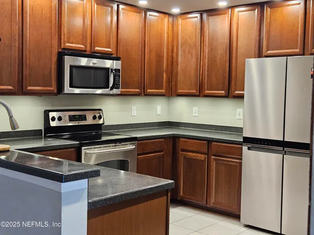 a kitchen with granite countertop a refrigerator stove and microwave