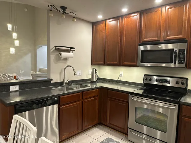 a kitchen with granite countertop a sink stainless steel appliances and cabinets