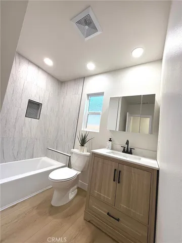 a bathroom with a double vanity sink toilet mirror and bathtub