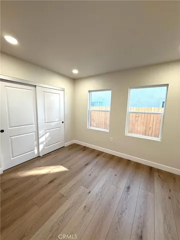 an empty room with wooden floor cabinet and windows