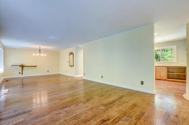 a view of a room with a chandelier fan and wooden floor