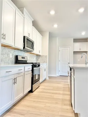 a kitchen with stainless steel appliances granite countertop a refrigerator a stove top oven a sink and dishwasher with wooden floor