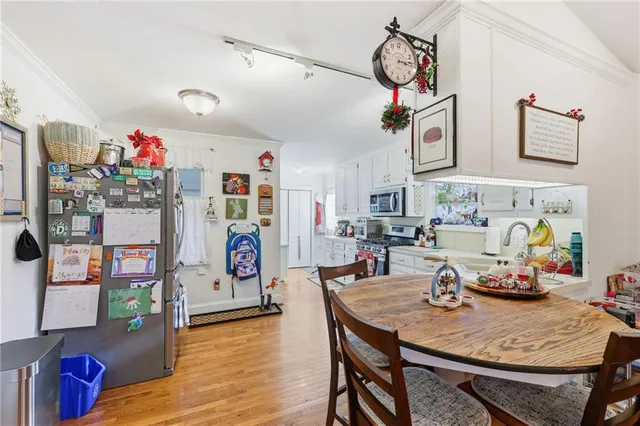 a kitchen with stainless steel appliances a stove a sink a refrigerator cabinets and a dining table with wooden floor