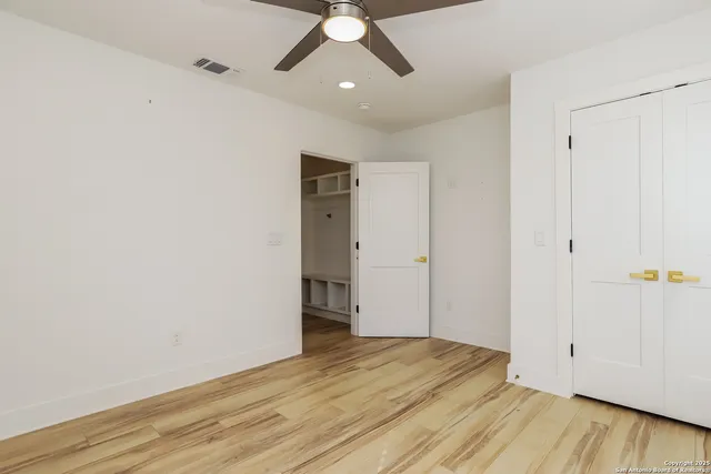 an empty room with wooden floor and ceiling fan