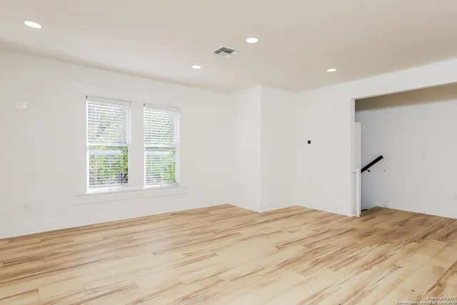 a view of empty room with wooden floor and fan