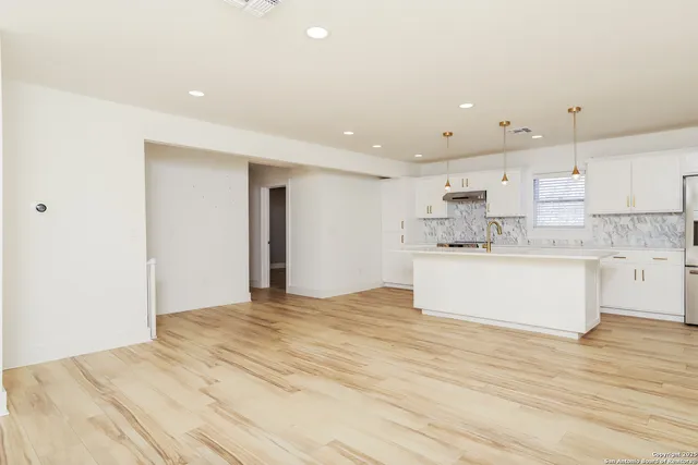 a large white kitchen with kitchen island a sink stainless steel appliances and cabinets
