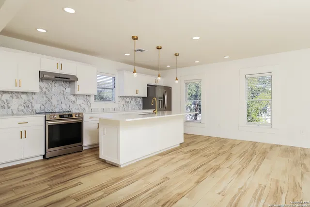 a large kitchen with stainless steel appliances kitchen island a large counter top and a wooden floors