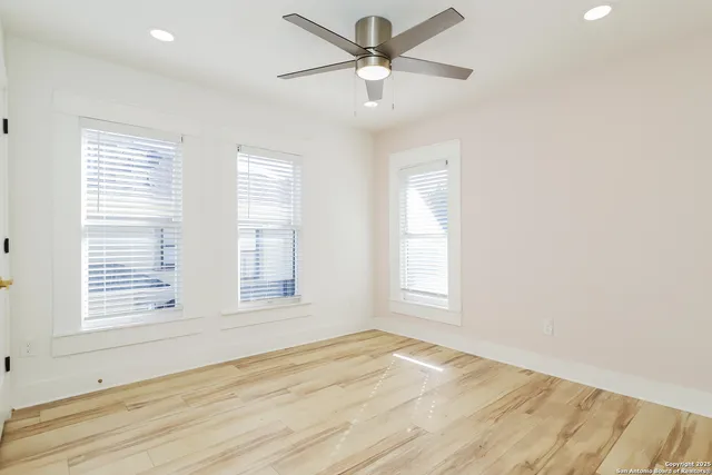 a view of an empty room with wooden floor and a window