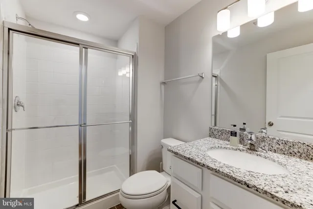 a bathroom with a granite countertop sink toilet and shower