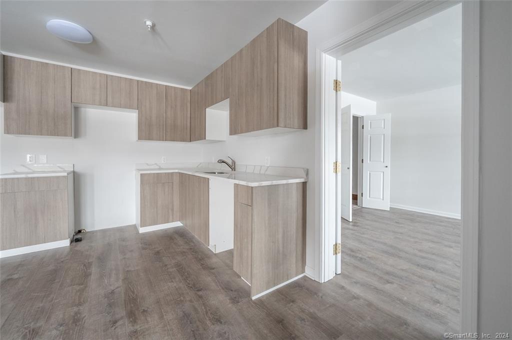 1030 Federal Road, Unit 204 Brookfield, CT 06804 - Photo 17 of 22 a view of a kitchen with an empty space and a refrigerator