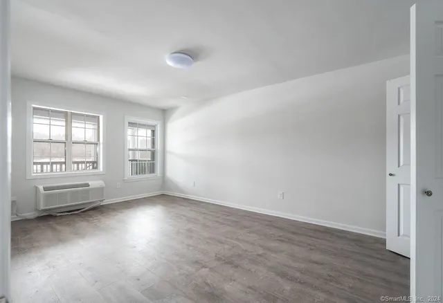 an empty room with wooden floor and windows