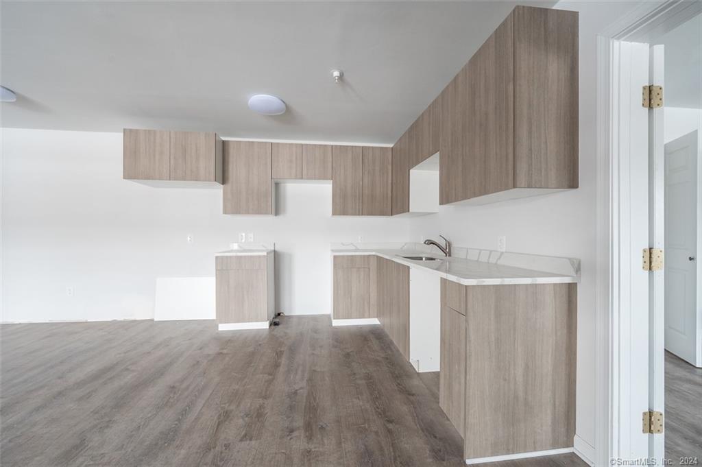 1030 Federal Road, Unit 204 Brookfield, CT 06804 - Photo 6 of 22 a view of a kitchen with white cabinets and wooden floor