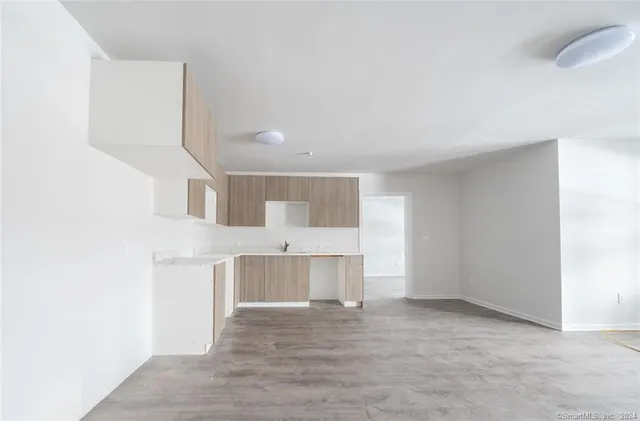 a view of kitchen and empty room with wooden floor