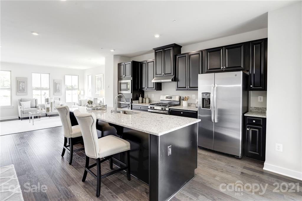 662 Crudent Road, Unit 1008B Tega Cay, SC 29708 - Photo 4 of 12 a kitchen with stainless steel appliances a table chairs refrigerator and microwave