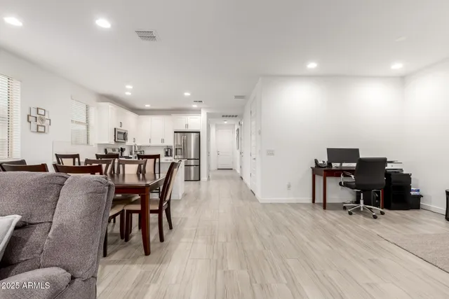 a living room with furniture and a dining table with wooden floor
