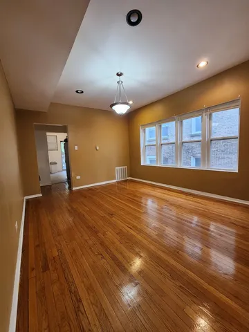 a view of an empty room with window and wooden floor