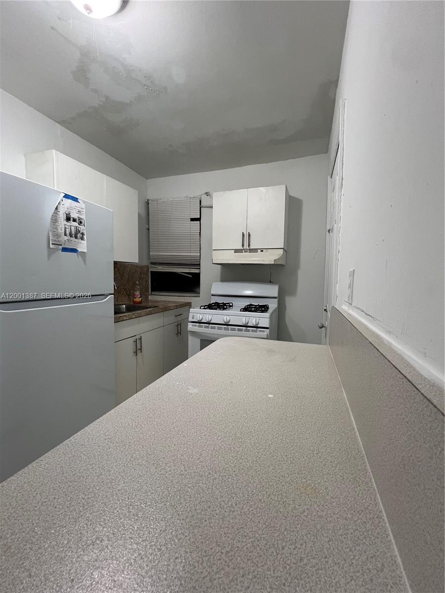 413 Northwest 33rd Street, Unit A Miami, FL 33127 - Photo 4 of 8 a kitchen with cabinets and a stove top oven