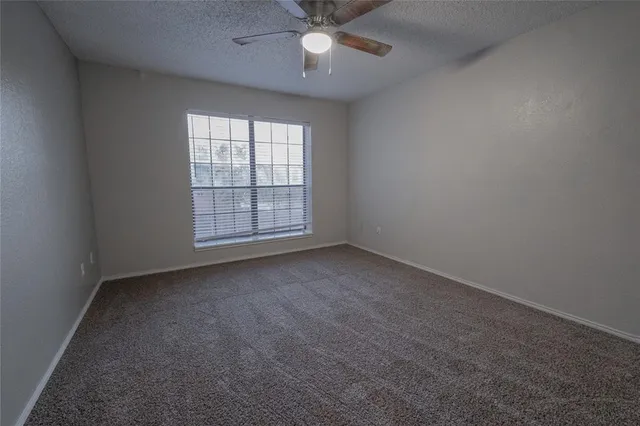an empty room with a ceiling fan and window