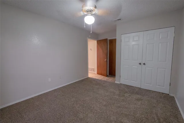an empty room with a chandelier fan and windows