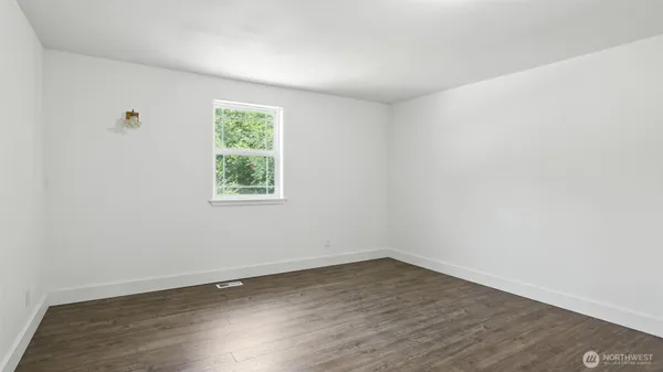 an empty room with wooden floor and window