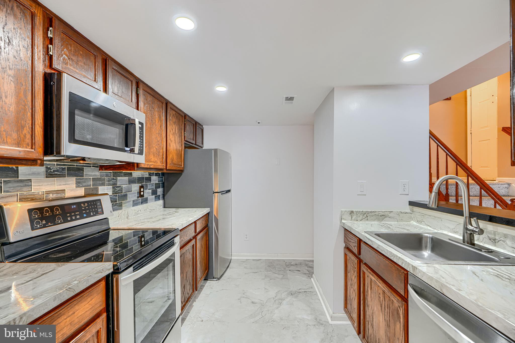 14235 Jib Street, Unit 7342 Laurel, MD 20707 - Photo 5 of 25 a kitchen with stainless steel appliances granite countertop a sink stove and refrigerator