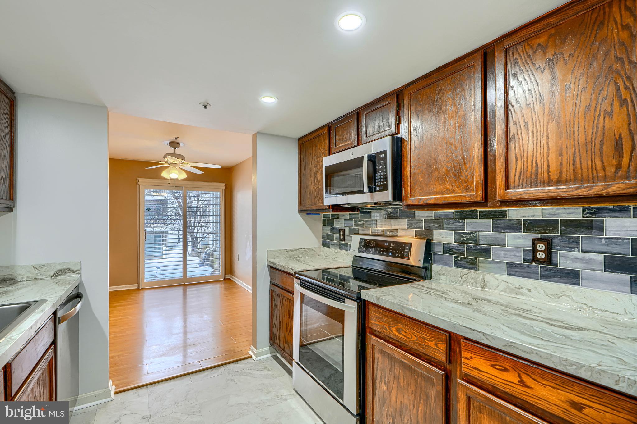 14235 Jib Street, Unit 7342 Laurel, MD 20707 - Photo 8 of 25 a kitchen with stainless steel appliances granite countertop wooden cabinets a stove top oven a sink and dishwasher