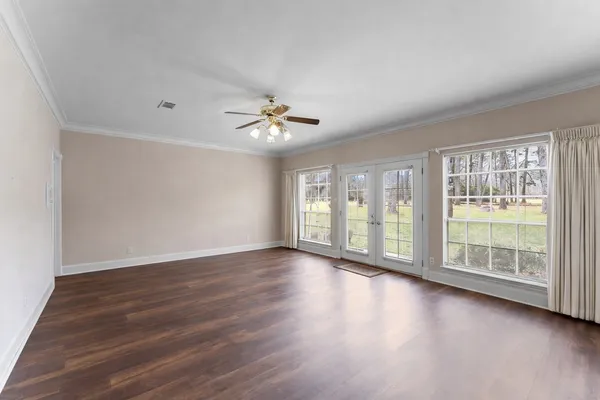 a view of an empty room with wooden floor and a window