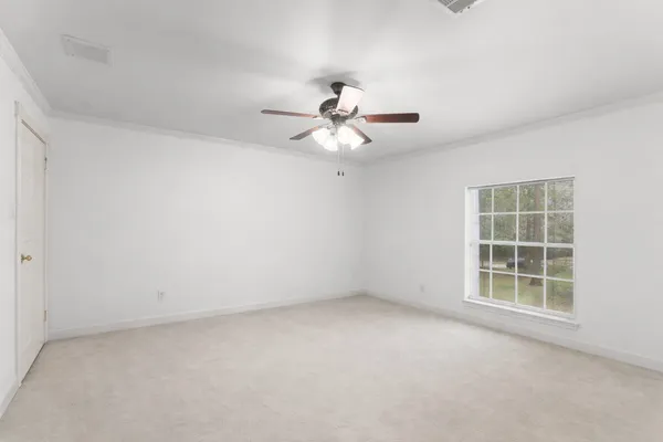 an empty room with a chandelier fan and windows