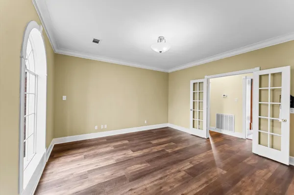 an empty room with wooden floor and windows