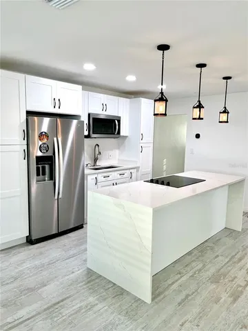 a kitchen with kitchen island white cabinets and stainless steel appliances
