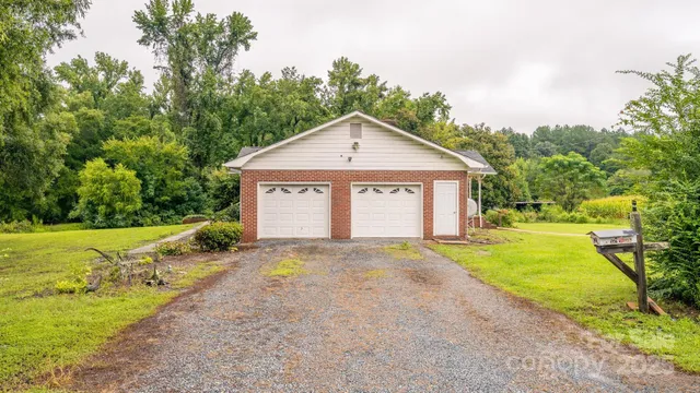 a view of a house with a yard and large trees