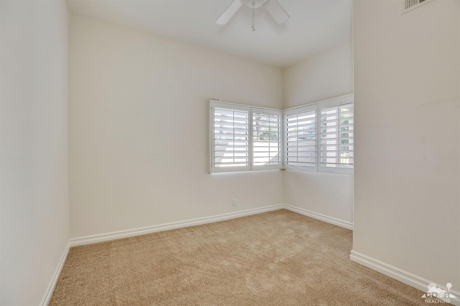 64 Oak Tree Drive Rancho Mirage, CA 92270 - Photo 21 of 31 an empty room with windows and chandelier fan