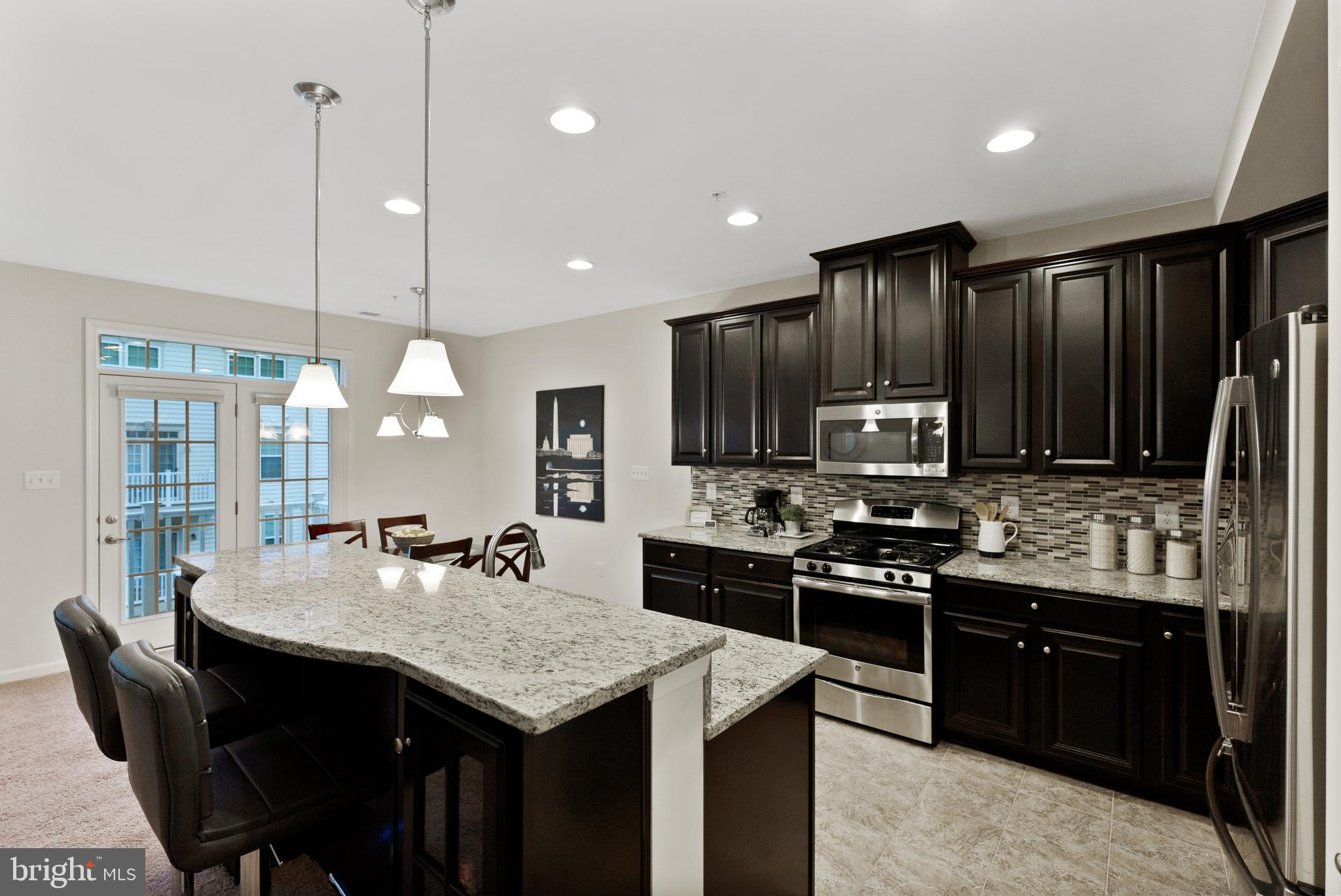 a kitchen with stainless steel appliances granite countertop a stove a sink a microwave a dining table and chairs