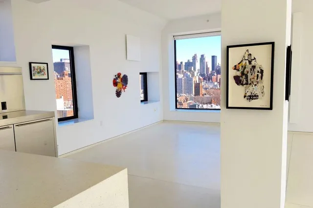 a view of a living room with painting on the wall and a refrigerator