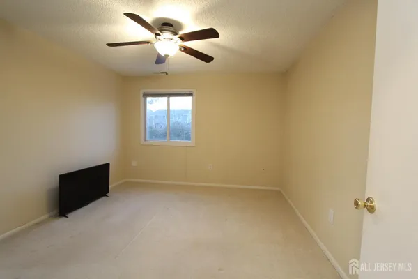 an empty room with ceiling fan and windows