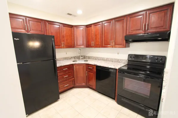 a kitchen with granite countertop a refrigerator stove and cabinets