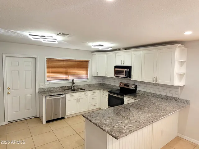 a kitchen with stainless steel appliances granite countertop a sink stove and refrigerator