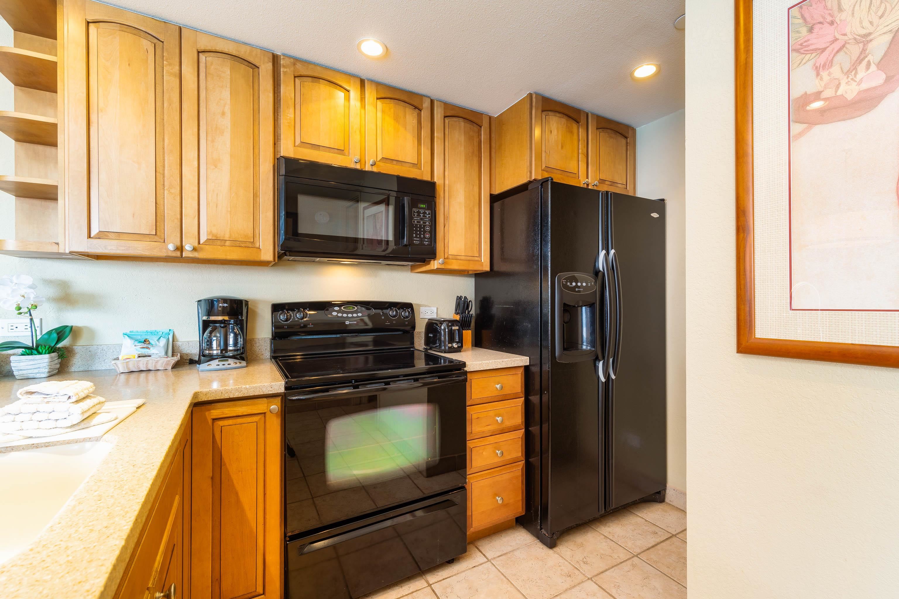 3445 Lower Honoapiilani Road, Unit 905 Lahaina, HI 96761 - Photo 11 of 30 a kitchen with granite countertop wooden cabinets stainless steel appliances and a window