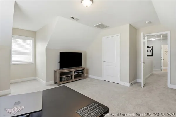 a living room with a flat screen tv a refrigerator and windows