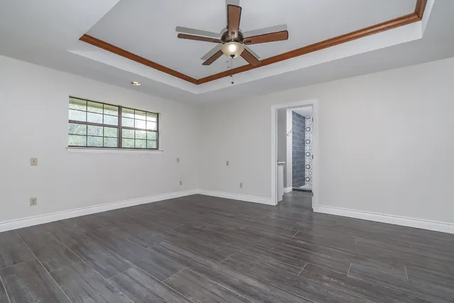 a view of an empty room with window and wooden floor