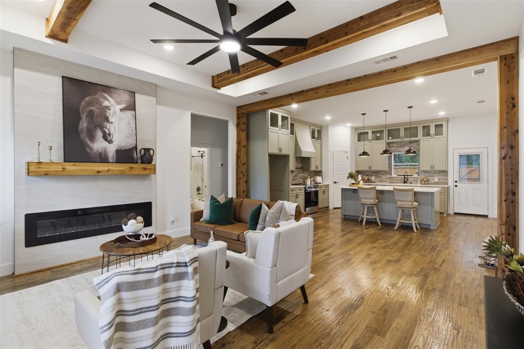 429 Waterboard Road Trinidad, TX 75163 - Photo 6 of 25 Open concept living area featuring a linear fireplace with wood mantel, wood-finish flooring, exposed wood beams, and a ceiling fan